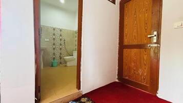 Un pasillo con una puerta de madera, una alfombra roja y un par de pantuflas azules en el suelo.