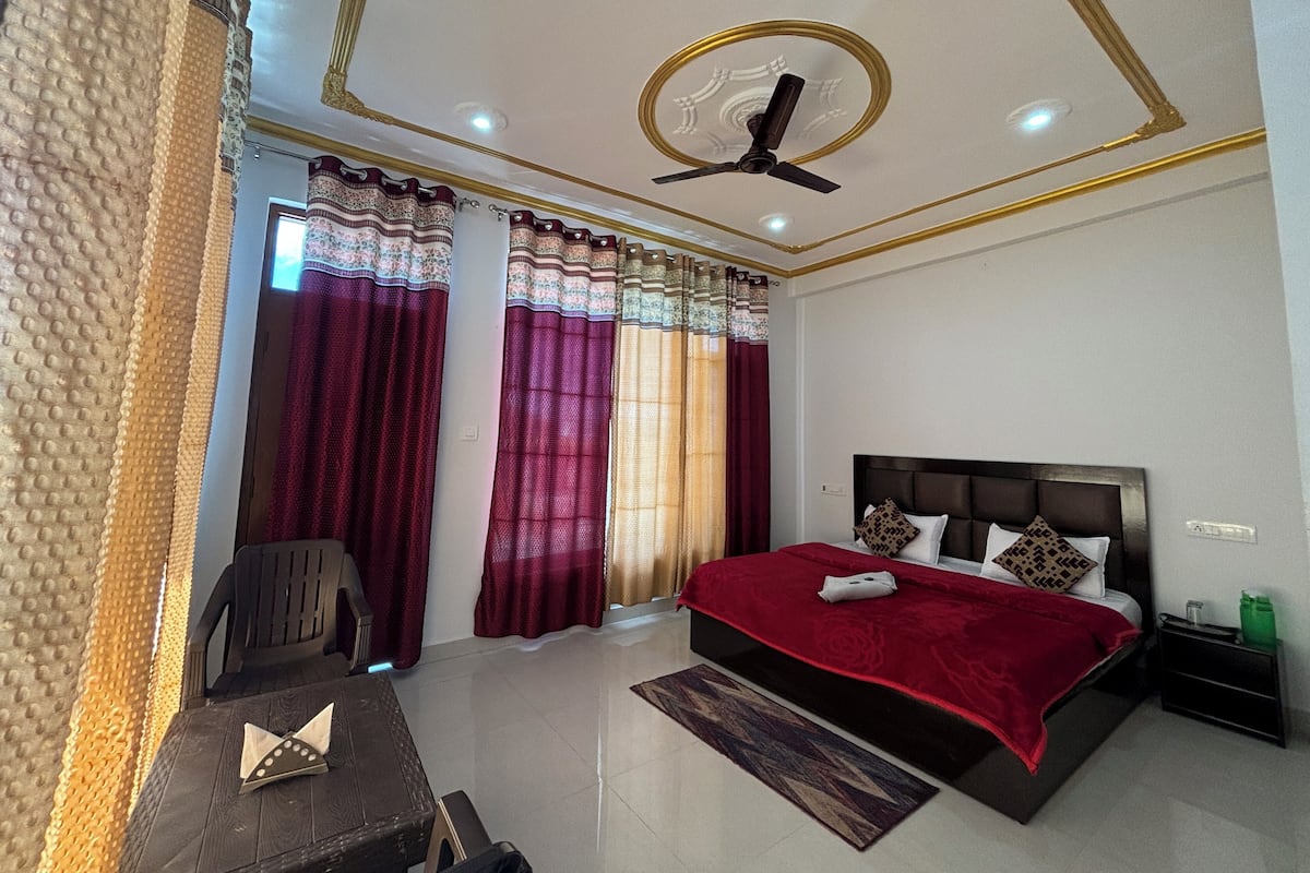A bedroom with a bed, a chair, a desk, and a ceiling fan.
