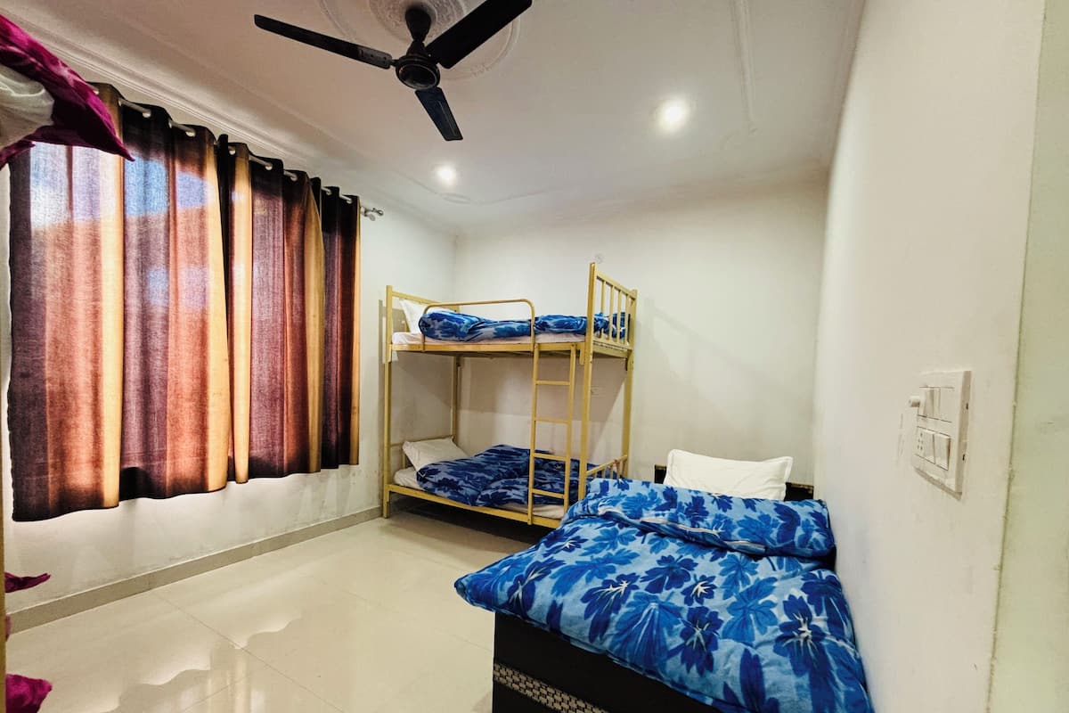 A room with bunk beds, a ceiling fan, and a window with curtains.