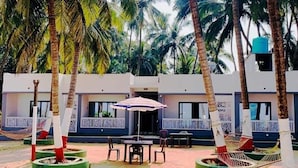 Un resort con varias cabañas, zonas de estar al aire libre y palmeras.