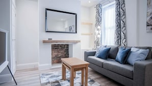 Una sala de estar con un sofá gris, una mesa de centro de madera y una chimenea.