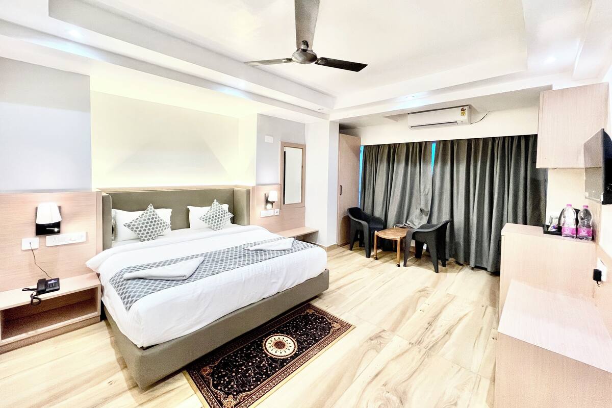 Une chambre d’hôtel moderne équipée d’un grand lit, d’un bureau, d’une chaise et d’un ventilateur de plafond.
