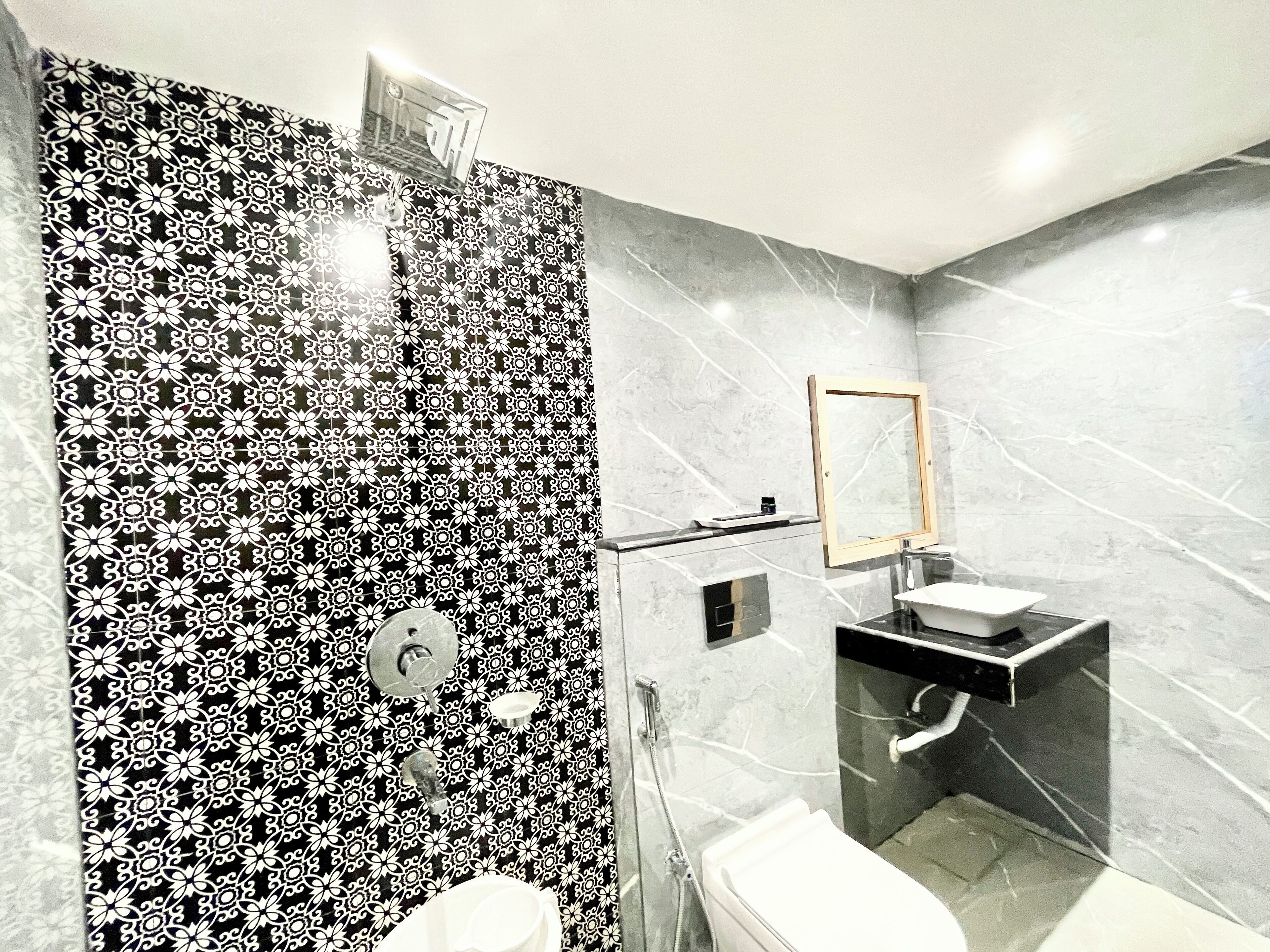 A modern bathroom with a black and white patterned shower wall, a standalone sink, and a mirror above it.