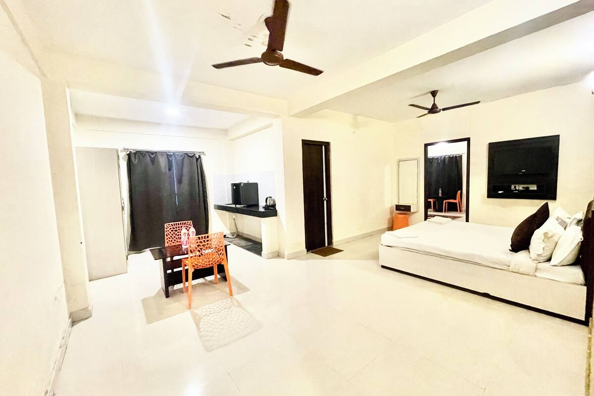 Une chambre d’hôtel équipée d’un lit, d’un bureau, d’une chaise, d’un ventilateur de plafond et d’une télévision.