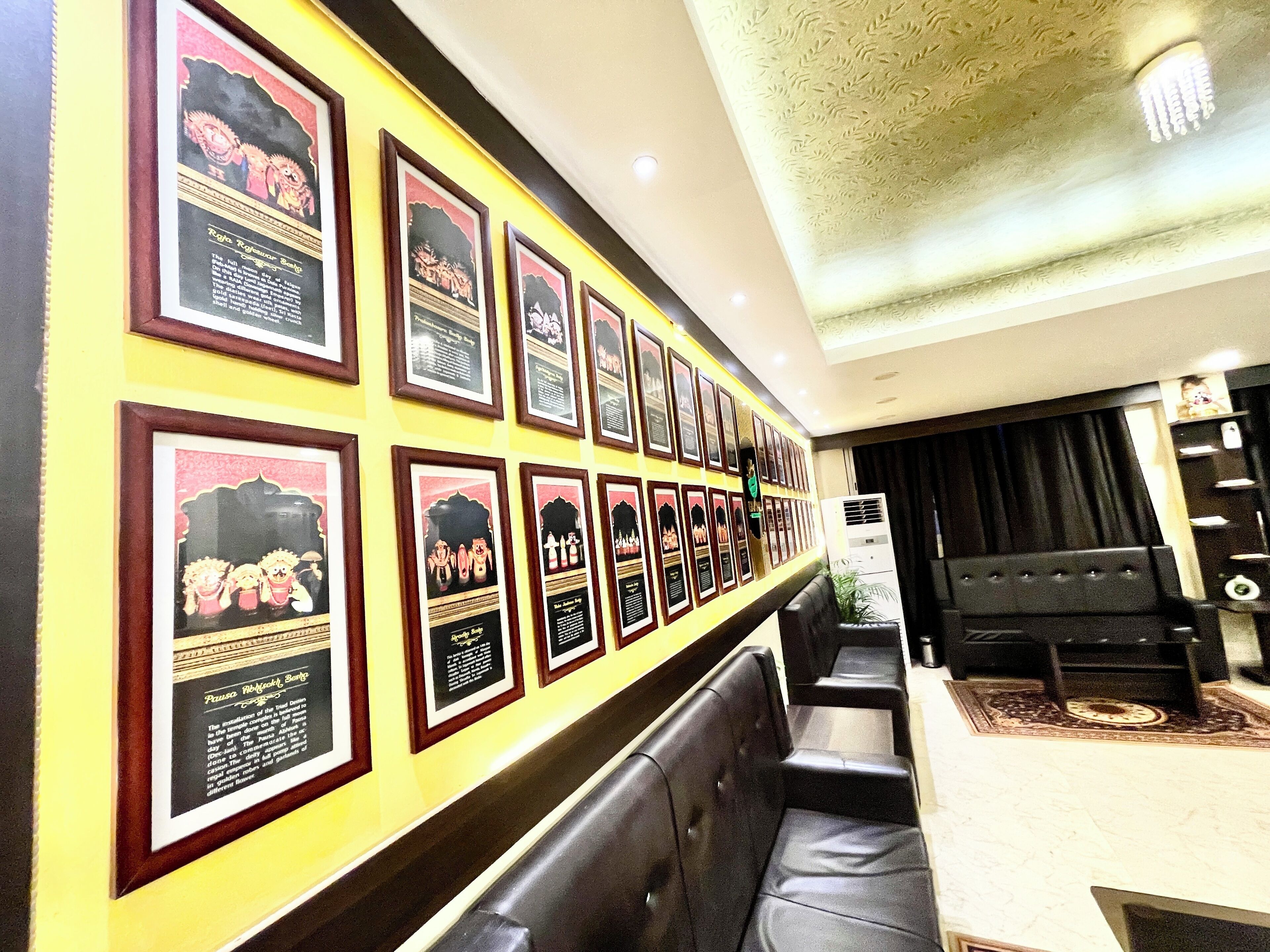 A wall with framed pictures and a seating area with black leather chairs and a table.