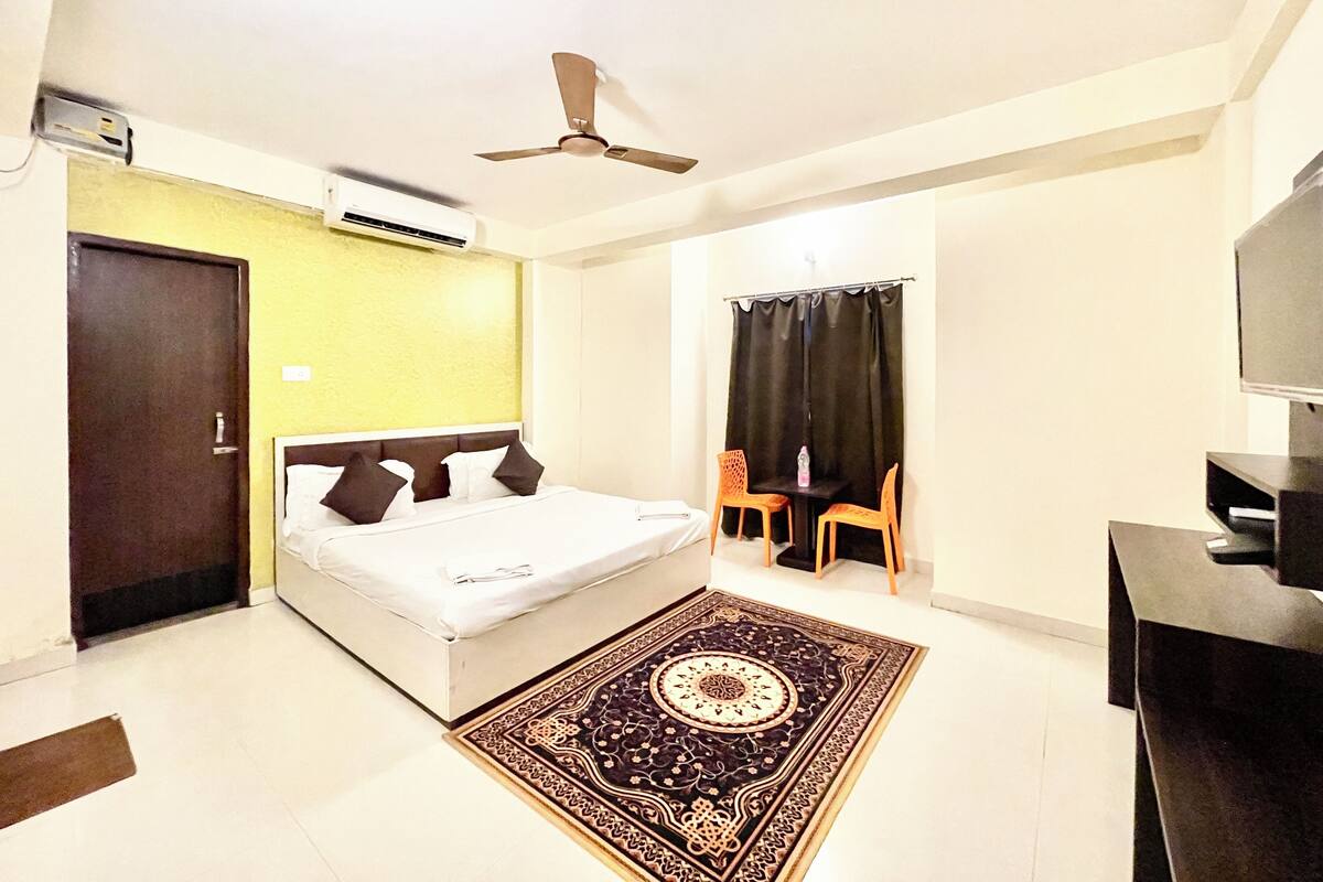 Une chambre à coucher comprenant un lit, un bureau, une chaise, un téléviseur et un ventilateur de plafond.