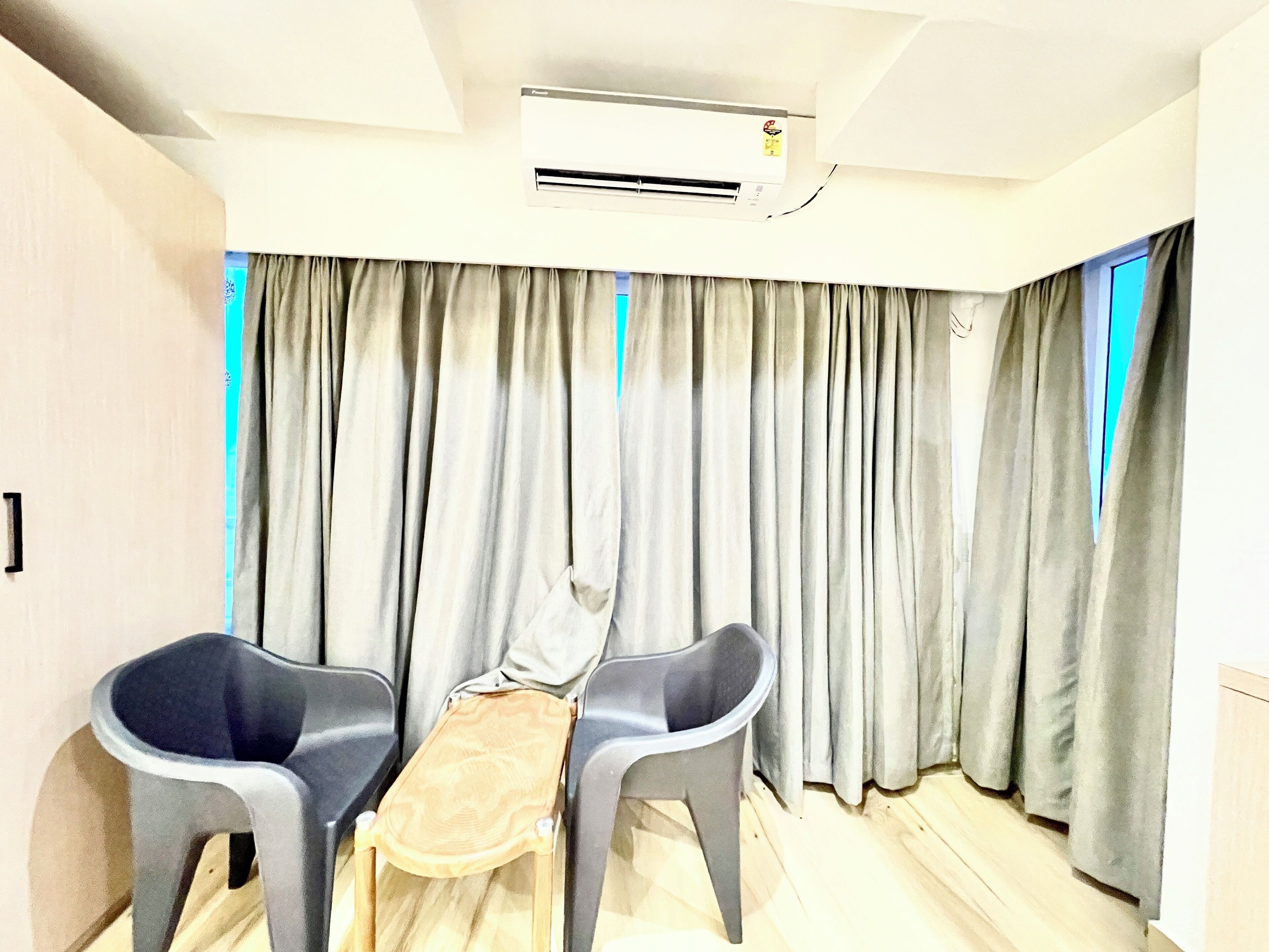 A room with a wooden table, two grey chairs, and grey curtains.