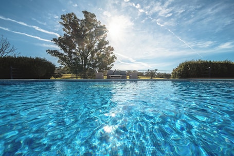 Una piscina al aire libre, sombrillas, sillones reclinables de piscina
