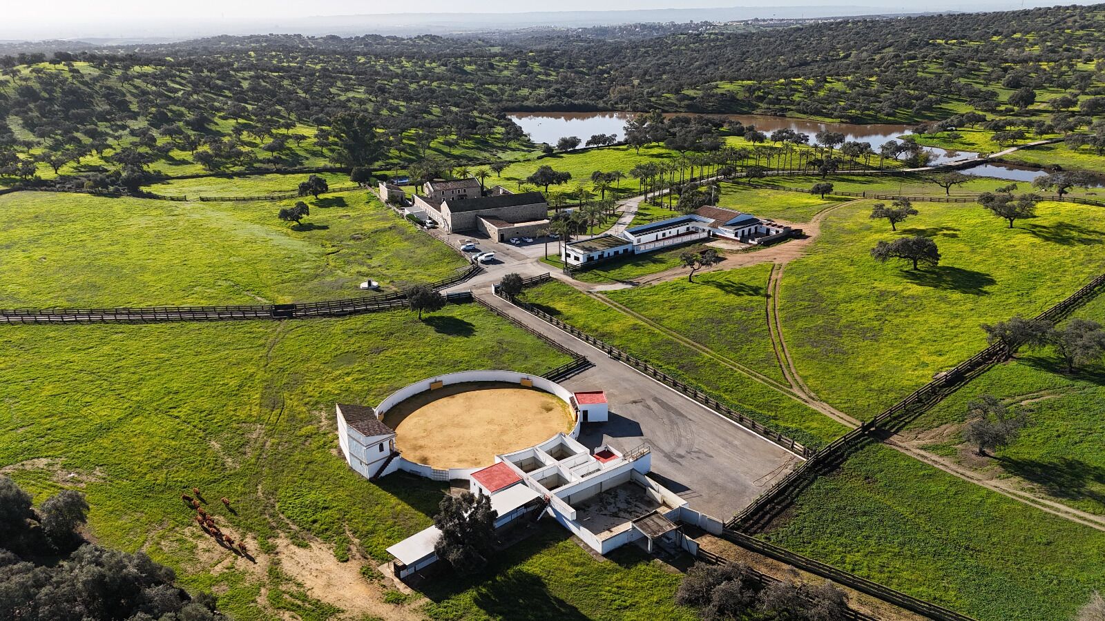 Luchtbeeld van een landgoed met een grote ronde arena, een boerderij en omliggende velden.