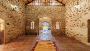 A stone-walled corridor with a wooden ceiling and a rug on the floor. - HOTEL RURAL FINCA BARRAL (Guillena)