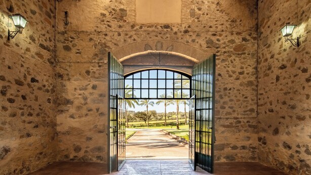 A stone-walled room with a tiled floor and an open door leading outside. - HOTEL RURAL FINCA BARRAL (Guillena)