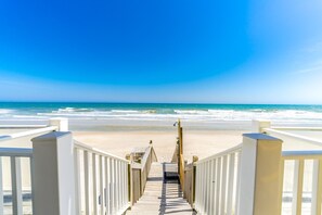 A wooden staircase leading to a beach with a clear blue sky.