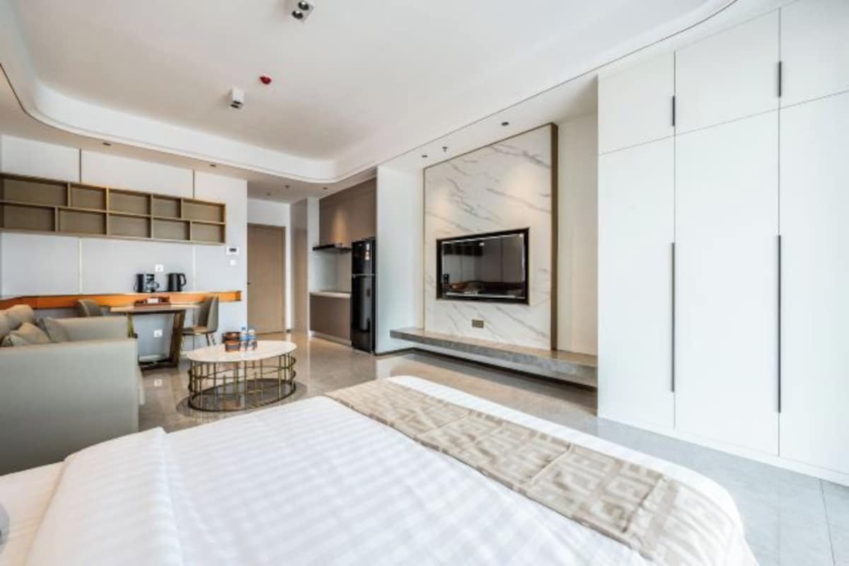Una camera d'albergo moderna con un letto grande, una TV a parete, un angolo cottura e un'area salotto.