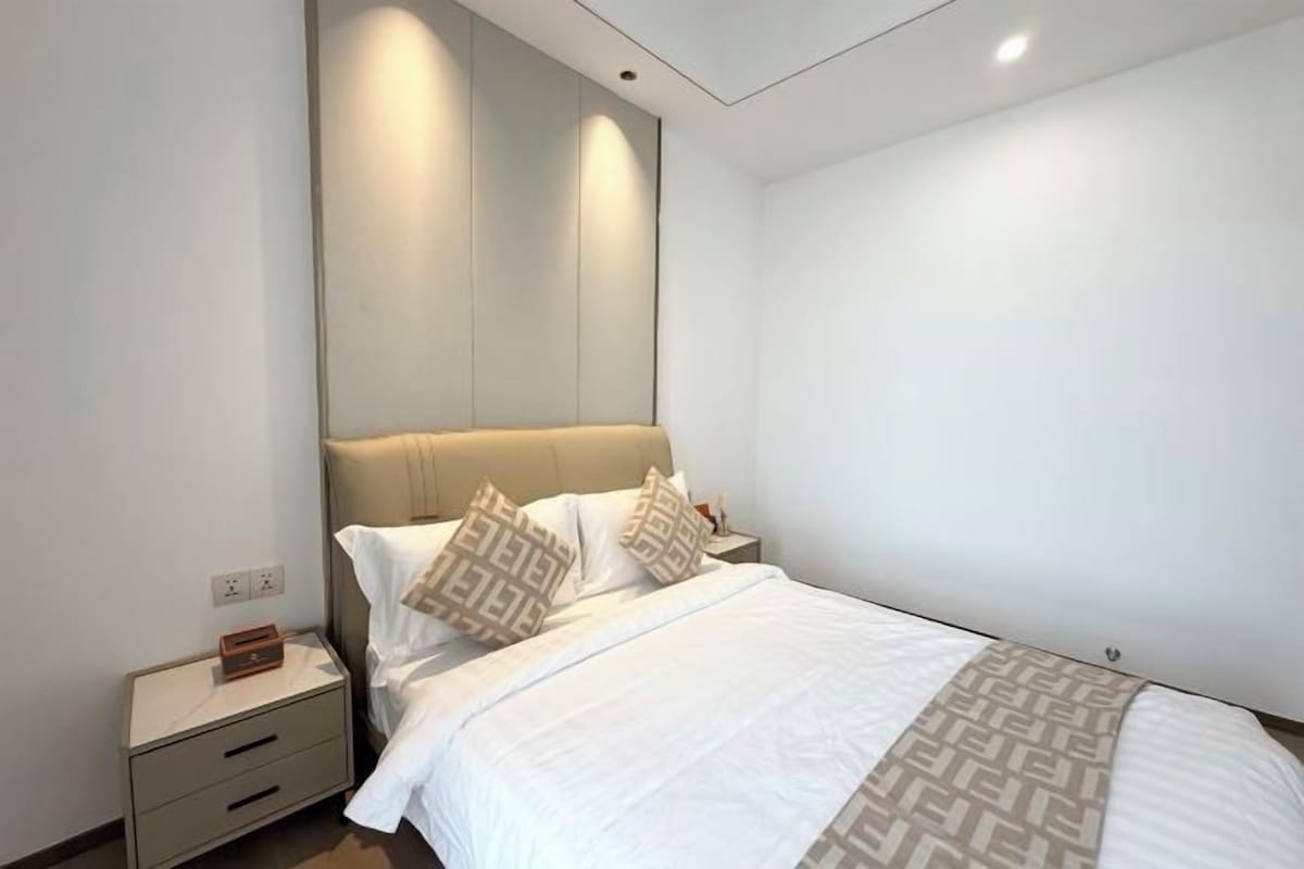 Un dormitorio moderno con una cama grande, mesitas de noche y cabecera.