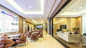 A modern hotel lobby with a reception desk, seating area with tables and chairs, and a large informational display on the wall. - Wealth Mansion Suite River View by Soben (Phnom Penh)