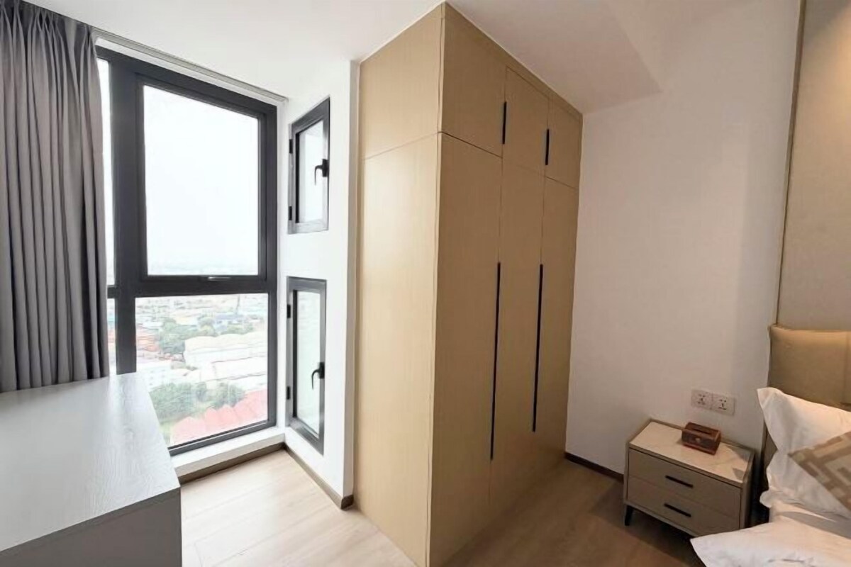 Un dormitorio con un armario grande, una mesita de noche y una ventana con cortinas.