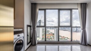 A spacious room with a large window offering a view of a river and cityscape. - Wealth Mansion Suite River View by Soben (Phnom Penh)