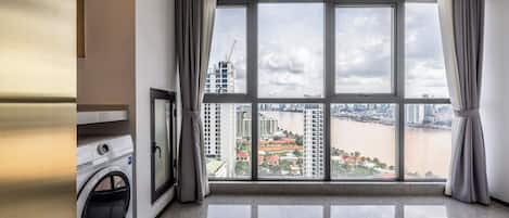 A spacious room with a large window offering a view of a river and cityscape.