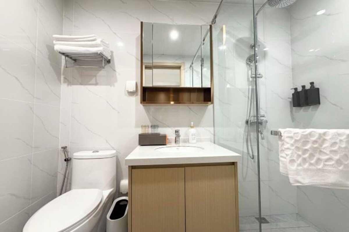 A modern bathroom with a toilet, sink, mirror, and shower.