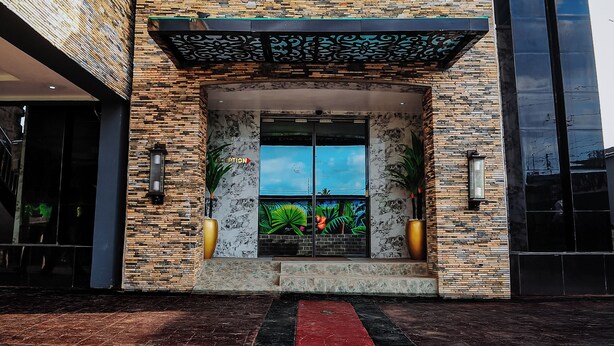 A building entrance with a modern design, featuring a patterned facade and a large glass door with a tropical mural. - Kashvalley Hotel and Suites (Lagos)
