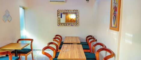 A dining area with wooden tables and chairs, a mirror, and a chandelier.