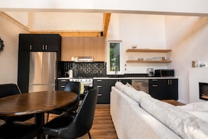A modern kitchen with a dining area, a sofa, and a fireplace.