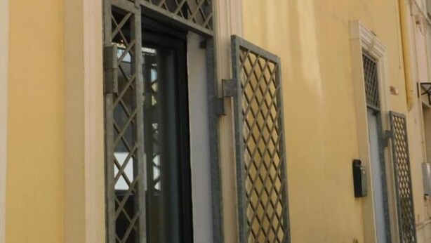 A building facade with a yellow wall, a metal gate, and a window with a lattice design. - SALENTO SEA AND ART (Nardò)