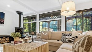 A modern living room with a large window, a wooden coffee table, and a sofa. - Relaxing Home Among The Redwoods - Dog-Friendly (Monte Rio)