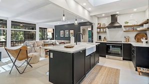 A modern kitchen with a central island, black cabinetry, and a large window. - Relaxing Home Among The Redwoods - Dog-Friendly (Monte Rio)