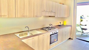 A modern kitchen with wooden cabinets, a stainless steel sink, a gas stove, and a built-in oven.