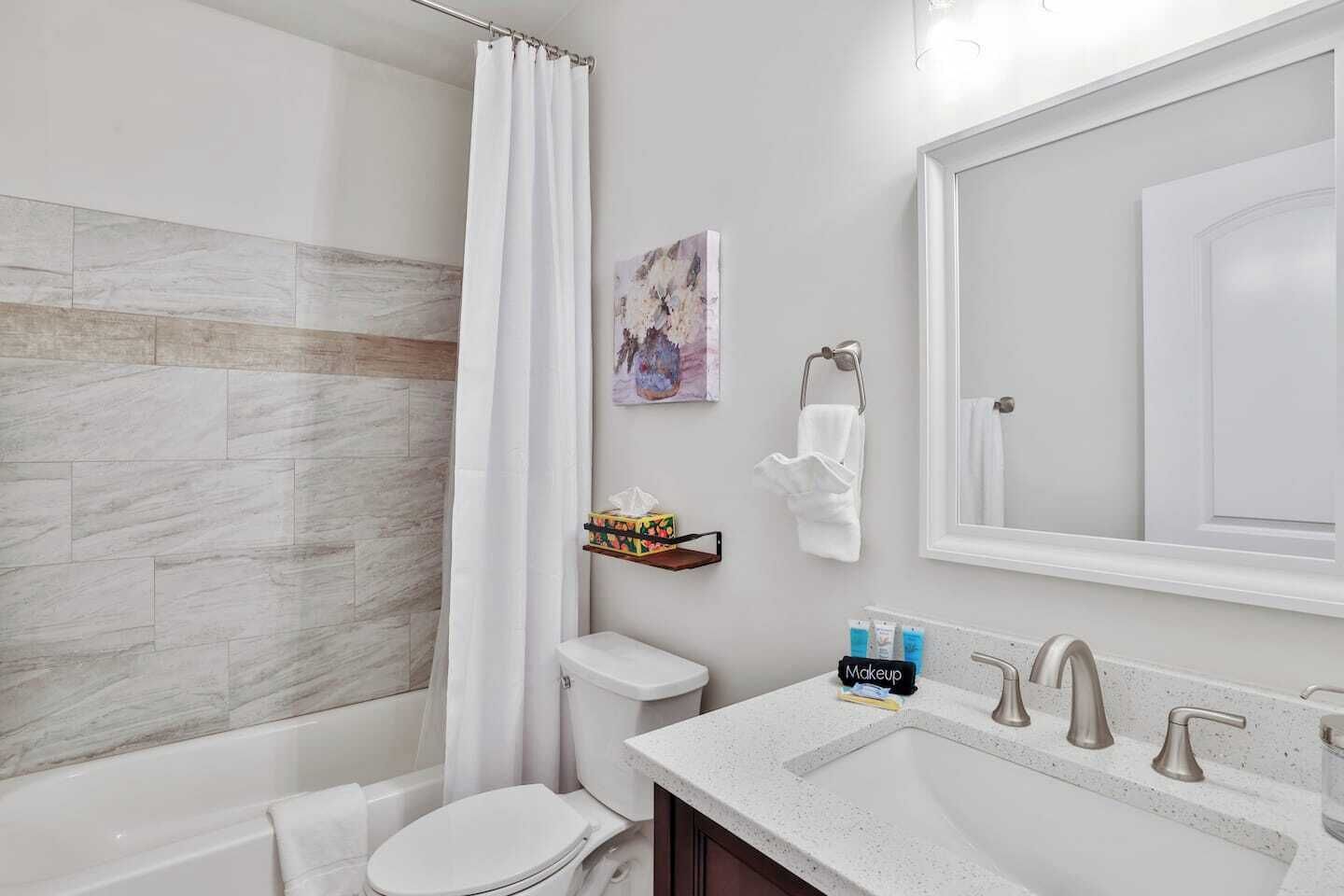 A bathroom with a shower, toilet, sink, and a mirror.