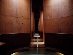 Un couloir doté d’un sol réfléchissant et de murs percés d’ouvertures circulaires.