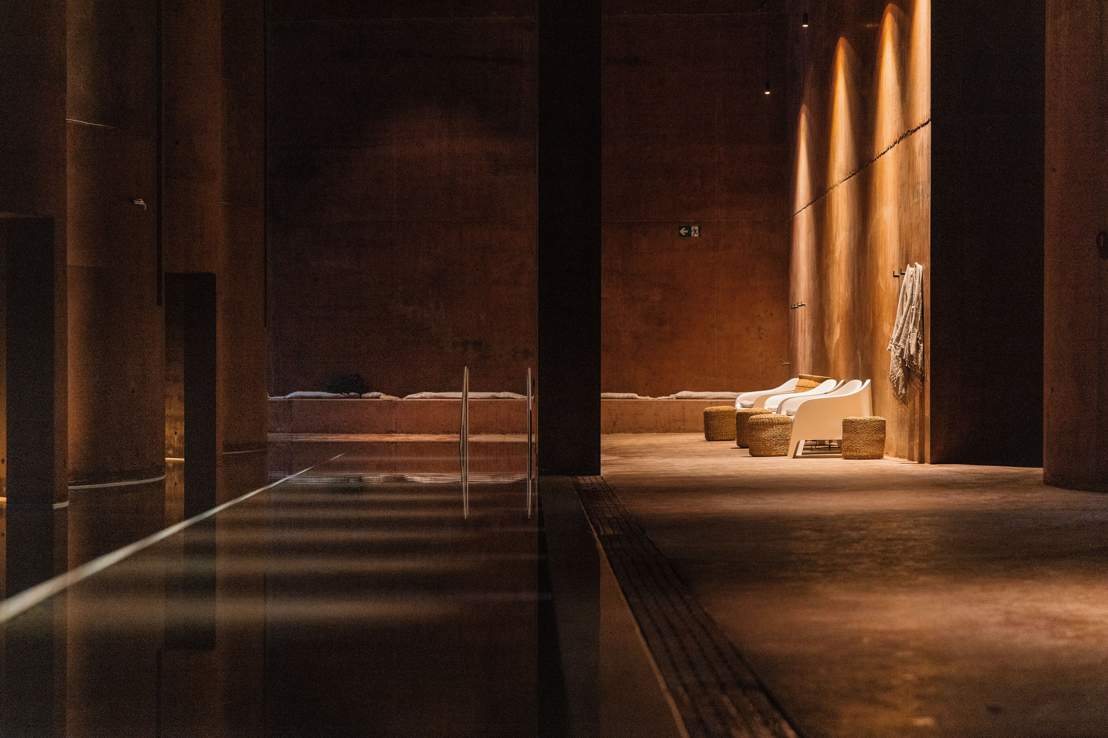 A spa area with a long, reflective floor, a seating area with chairs, and a towel rack.