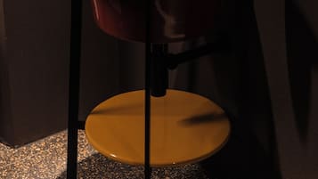 Une salle de bain moderne avec un lavabo orange original, un porte-serviettes avec des serviettes et un flacon de savon pour les mains.