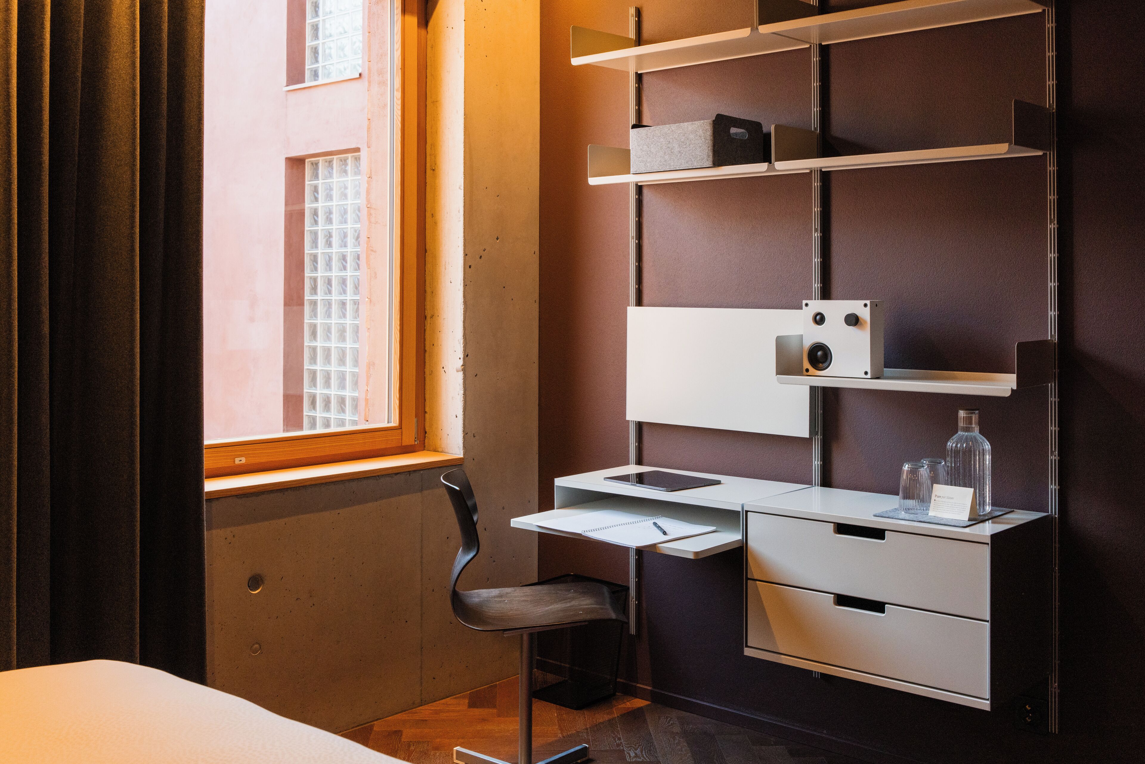 Una habitación de hotel moderna con escritorio, silla y estanterías empotradas.