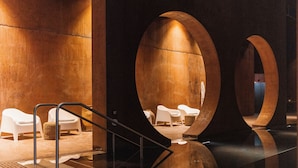 Un espace intérieur moderne doté d’un sol en verre, de chaises blanches et de grandes structures circulaires en béton.