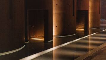 A corridor with large cylindrical columns and a reflective floor.
