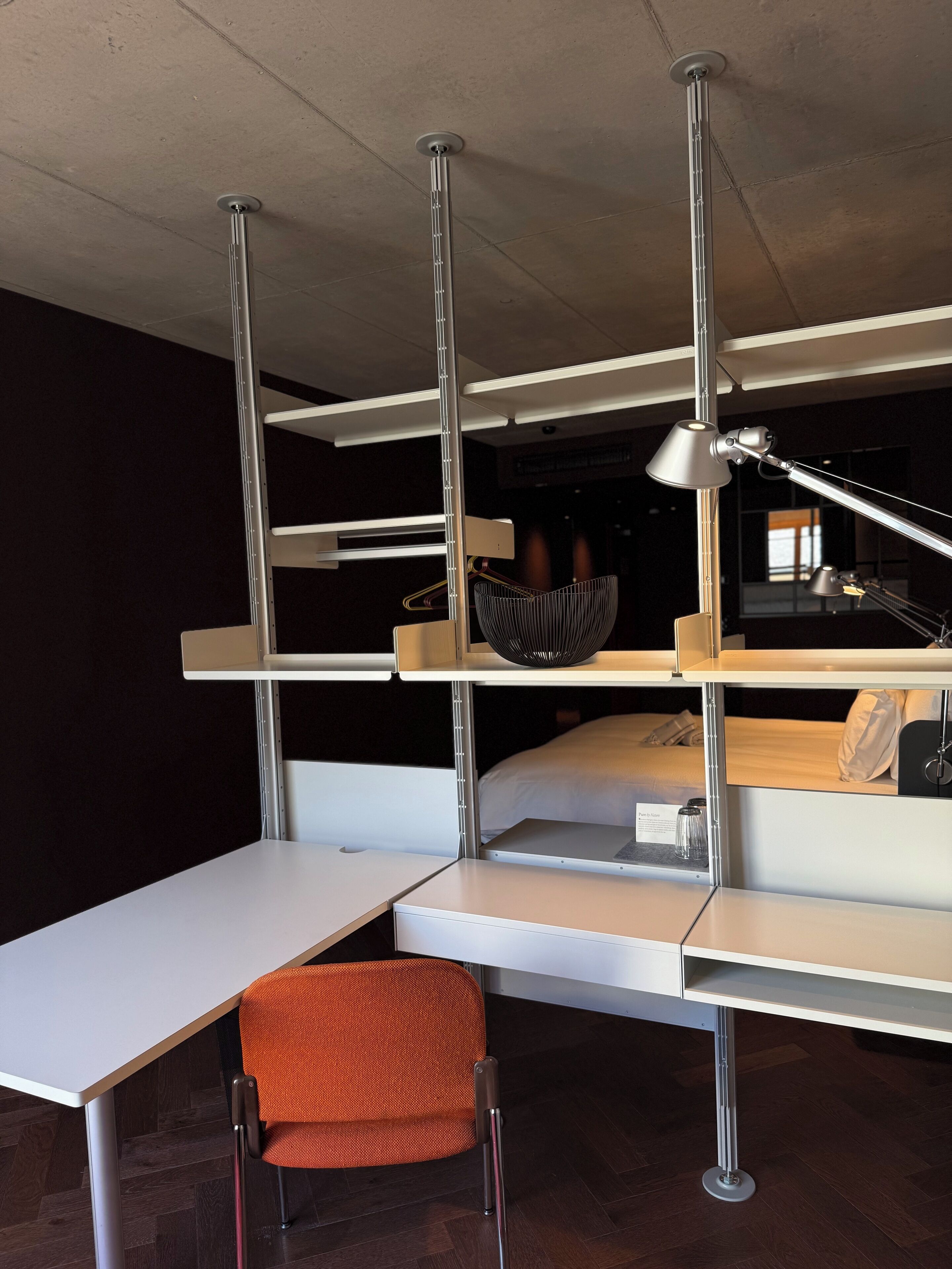 A compact hotel room with a bed, a desk, and a chair.