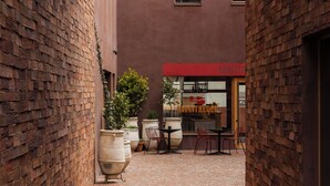 Une ruelle étroite en briques où se trouve un café appelé « Saucittheque », avec une terrasse et des plantes en pot.