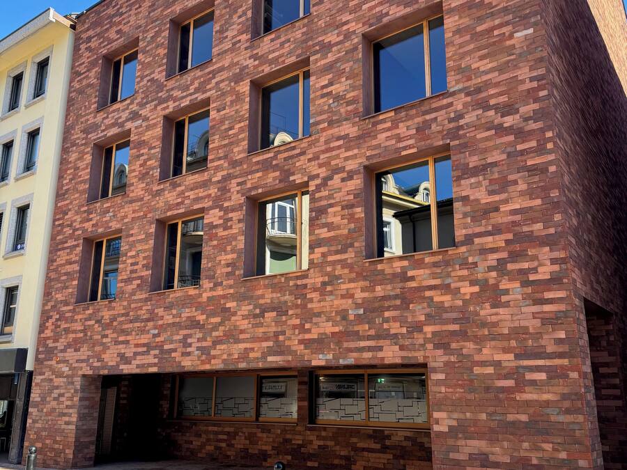 A multi-story building with a brick facade, large windows, and a ground-level entrance.