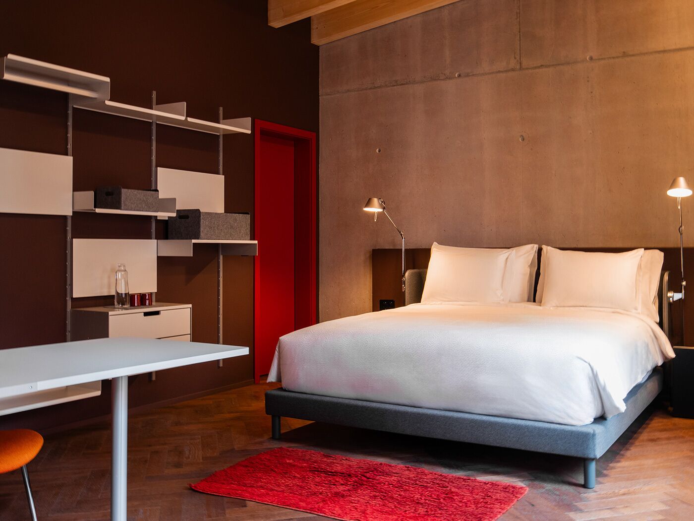 Un dormitorio moderno con una cama, mesitas de noche, un escritorio y una alfombra roja.