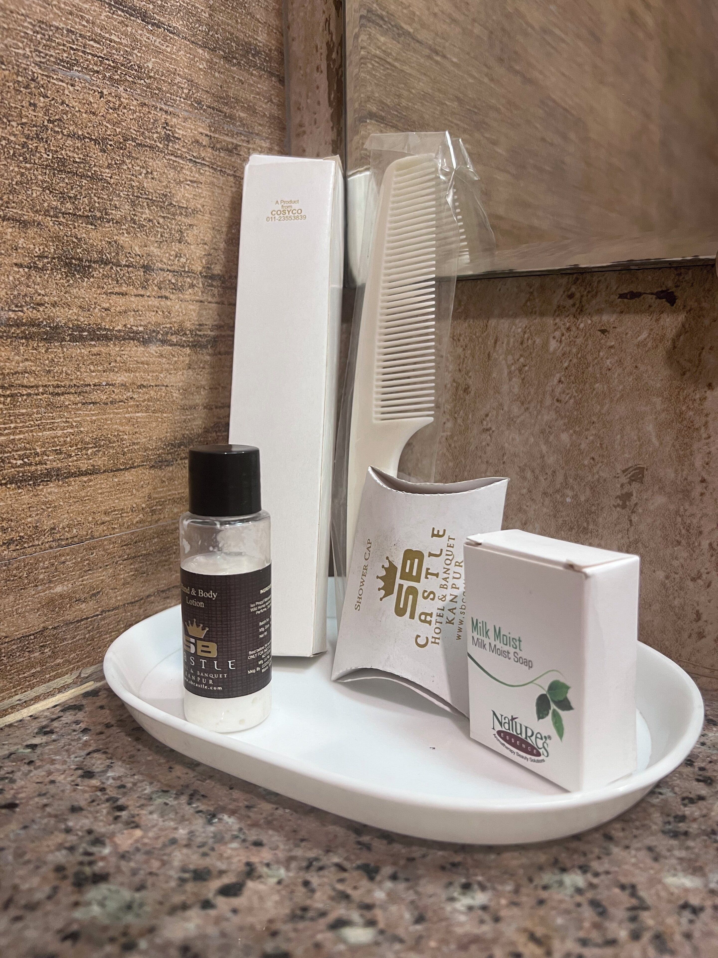 A tray with a bottle of shower cap, a comb, a box of shower cap, a box of milk soap, and a box of body lotion.