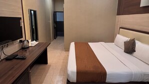 A hotel room with a bed, bedside table, TV, and a view of the hallway. - Hotel SB Castle  (Kanpur)