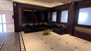 A spacious lobby with a polished tile floor, dark leather sofas, and a central glass coffee table. - Hotel SB Castle  (Kanpur)