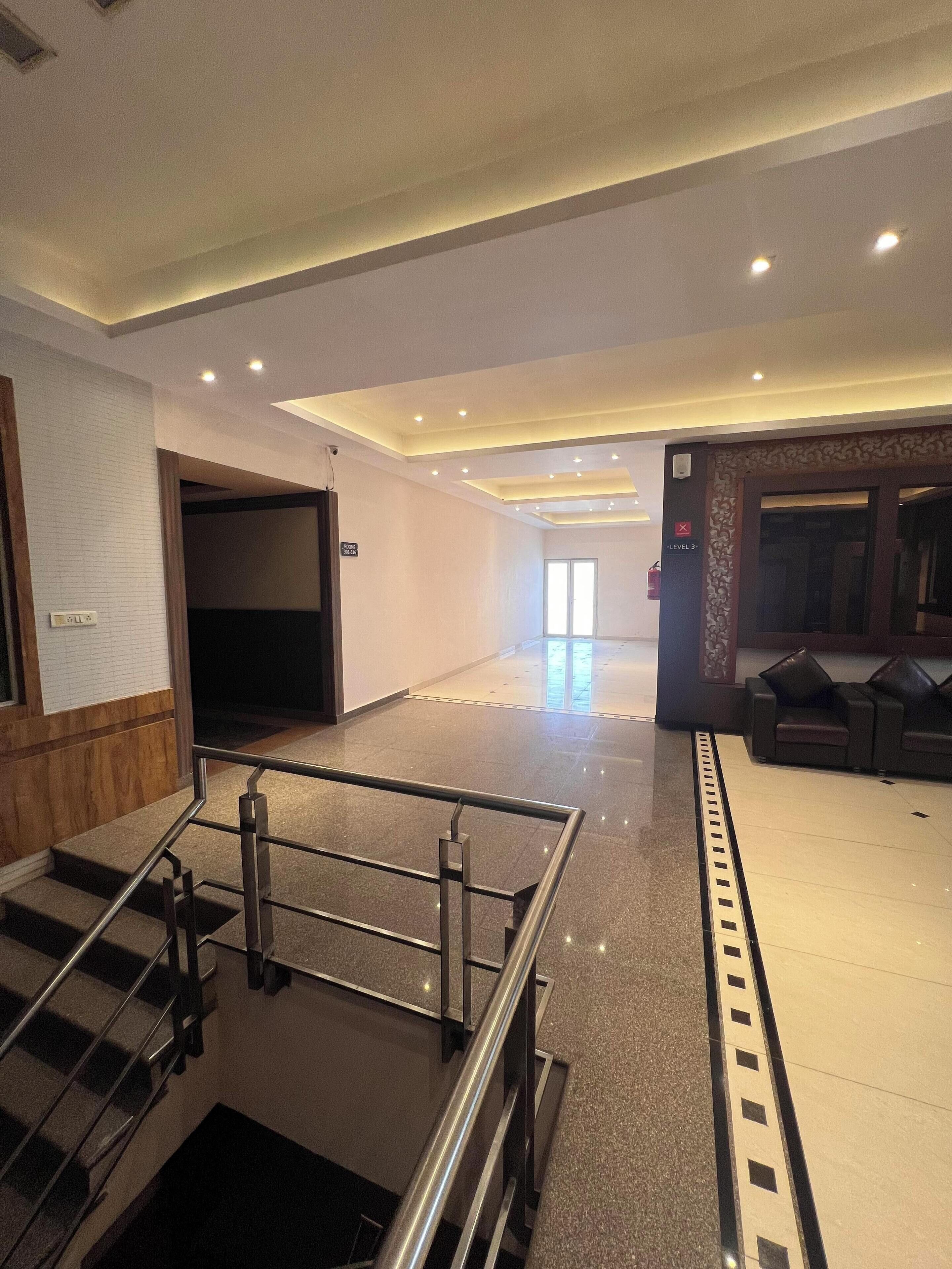 A hotel lobby with a staircase, a reception desk, and a seating area.