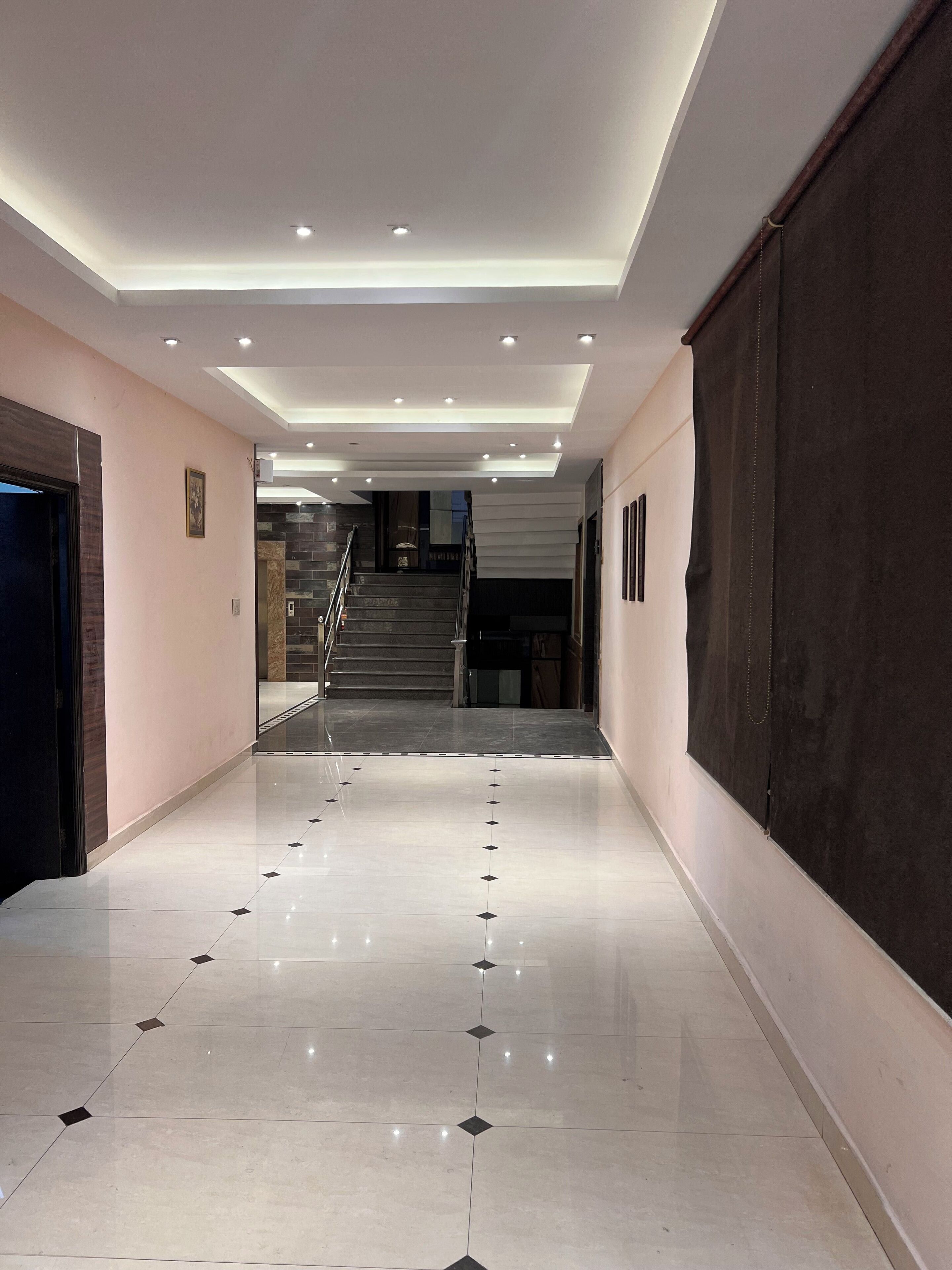Un couloir moderne avec un plancher poli, un escalier et un éclairage encastré.