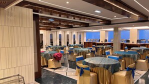 A banquet hall with round tables, chairs, and buffet stations. - Hotel SB Castle  (Kanpur)