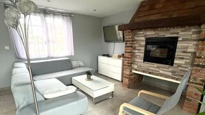 A living room with a sofa, coffee table, TV, fireplace, and a plant.