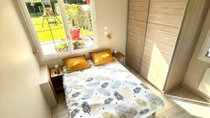 A bedroom with a bed, a window, a wardrobe, and a small table.