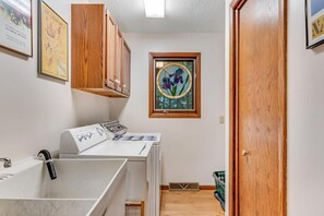 A laundry room with a washing machine, dryer, and wooden cabinets.